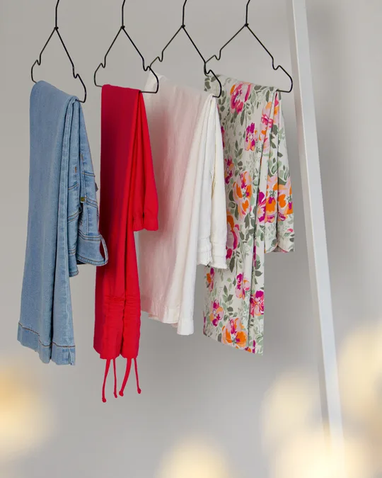 Jeans, röda byxor, vit skjorta och blommiga byxor på galgar