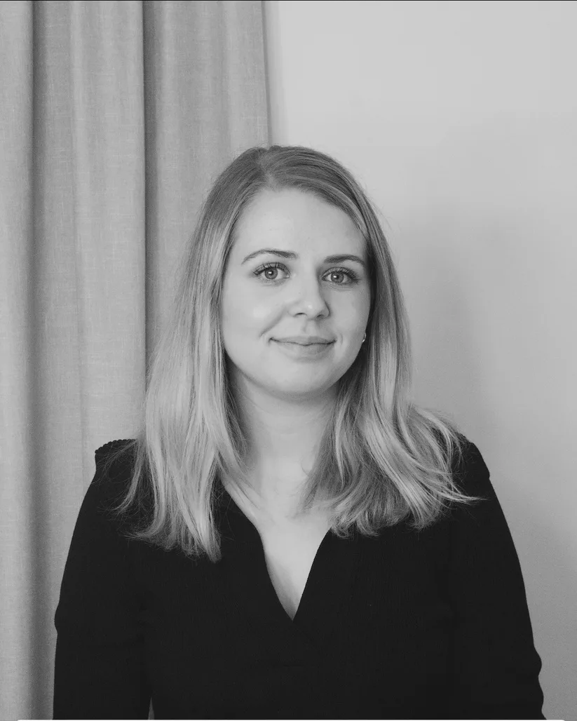 Porträtt av Frida Bergstrand i svart blus framför ett ljust draperi